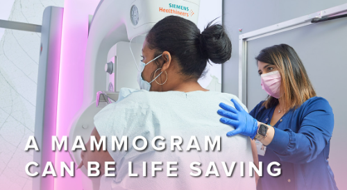 A woman receives a mammogram and stands next to a physician.